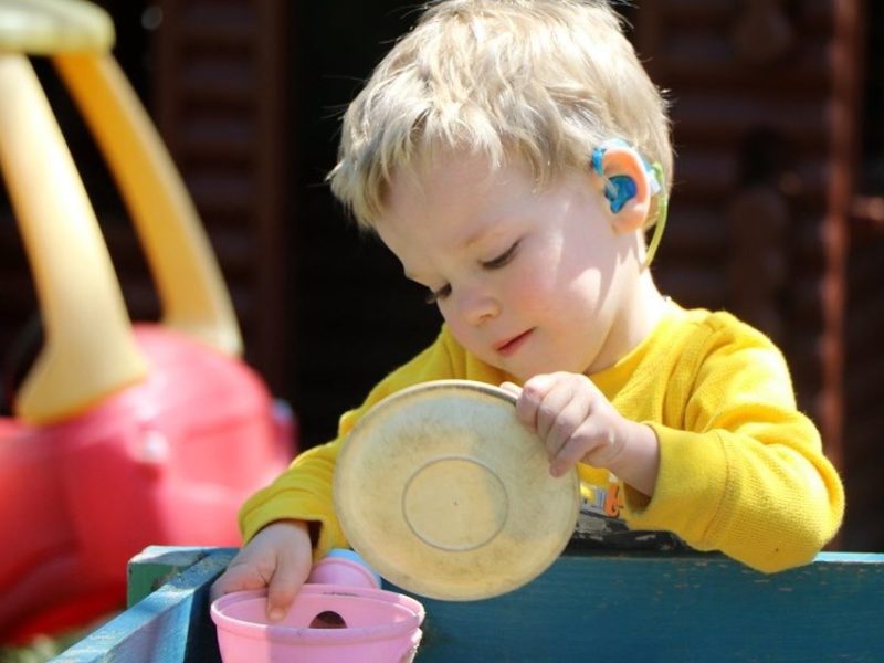 Three year old child playing in sandbox.