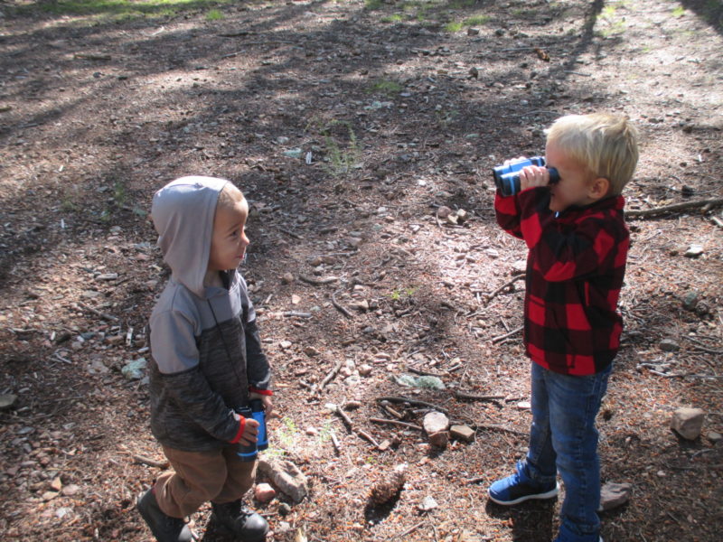 Preschooler viewing another preschooler through binoculars