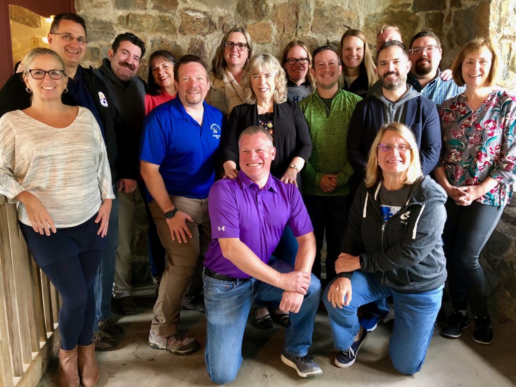 Group of 16 adults smiling for the picture.