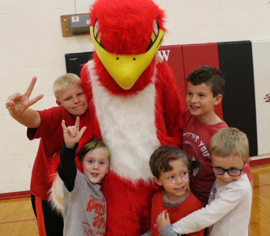 Four young children surrounding firebird mascot.