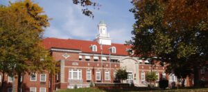 Long brick building with white window frames and a white cupola