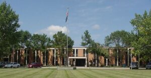 Long brick building with American flag and North Dakota flag flying on one pole in front.