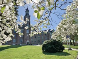 Large, two story building with tall cupola as seen through dogwood flowers.